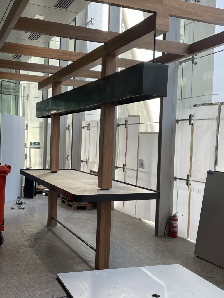 Suspended metal pot plant holder with timber posts inside a commercial interior