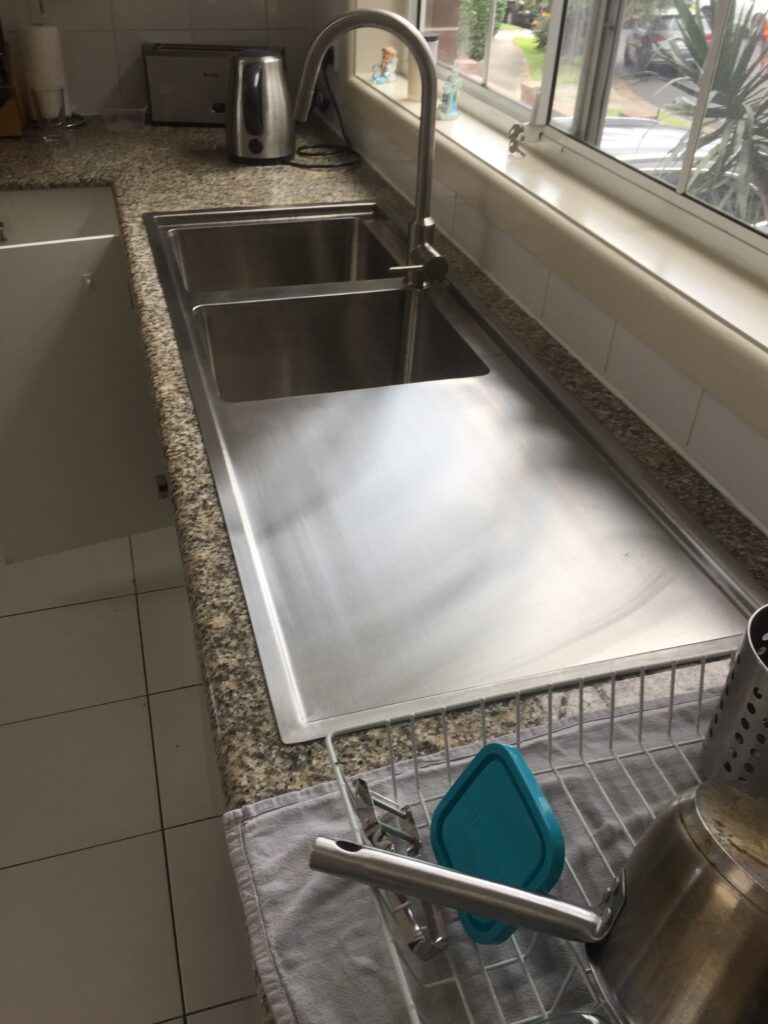 Drop‑in stainless steel sink with integrated drainer installed in a kitchen benchtop