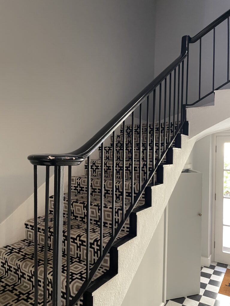 Internal steel stair balustrade with vertical bars beside an exposed brick wall