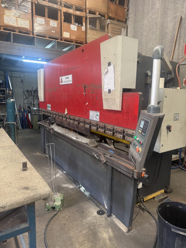 Hydraulic press brake machine bending stainless steel sheet, demonstrating forming limits based on machine size in a fabrication workshop