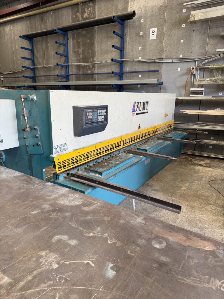 Guillotine machine cutting stainless steel sheet, demonstrating straight-line cutting and maximum sheet size limits in fabrication
