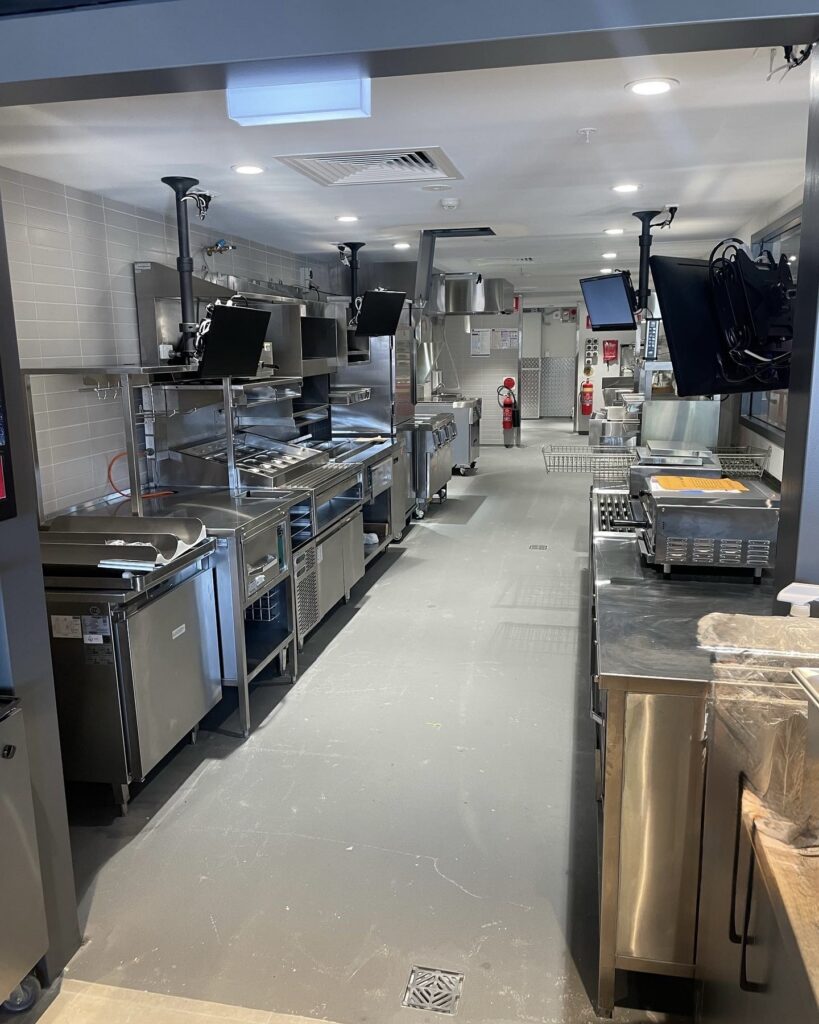 Commercial kitchen layout showing efficient workflow with clear walkways, stainless steel equipment alignment, and organised workstations
